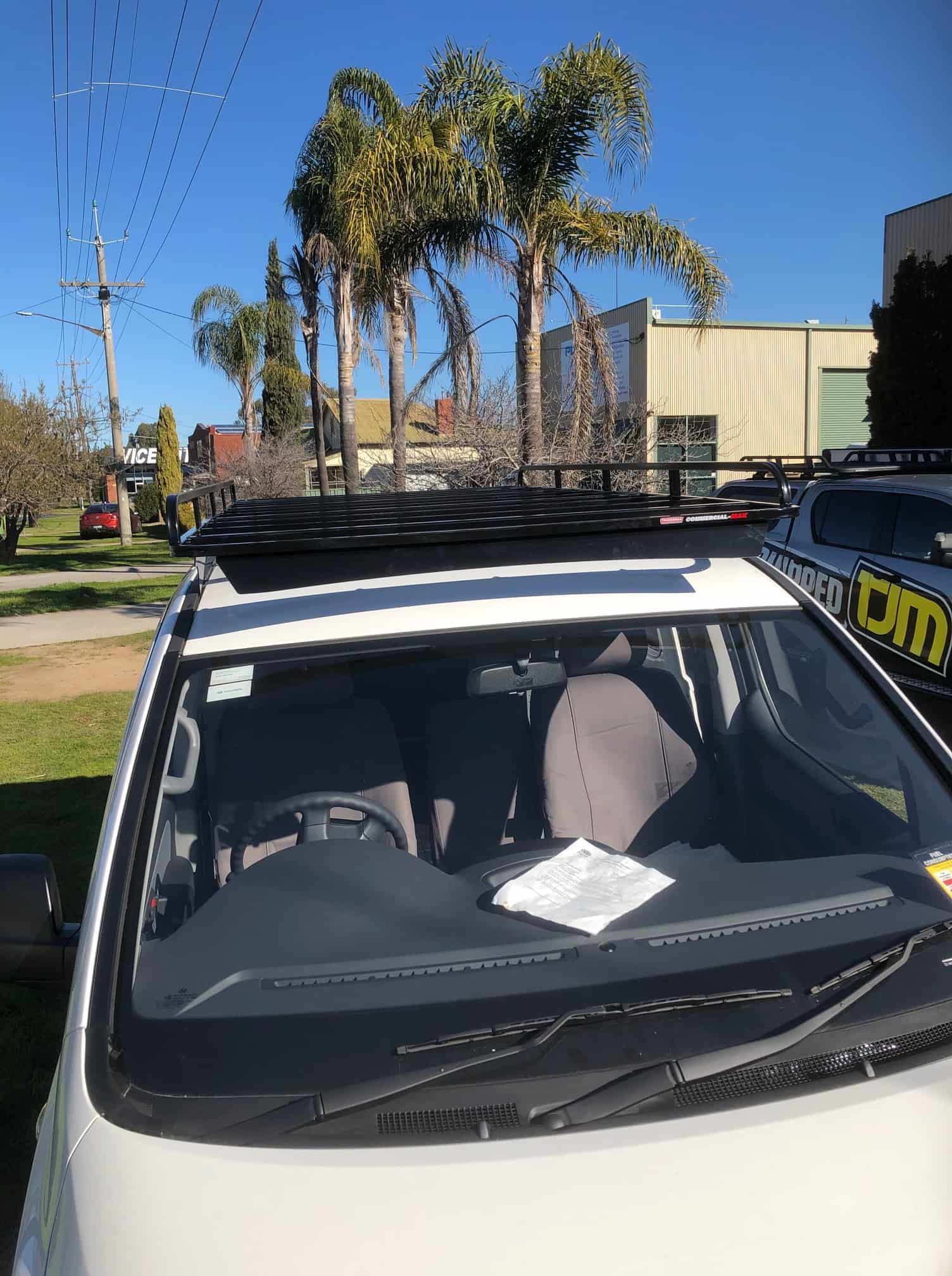 White Van With Roof Rack Parked in Front of a Building With Palm Trees — TJM Albury Pty Ltd in South Albury, NSW