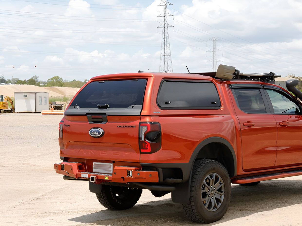 An Orange Truck With a Roof Rack is Parked in a Dirt Lot — TJM Albury Pty Ltd in South Albury, NSW