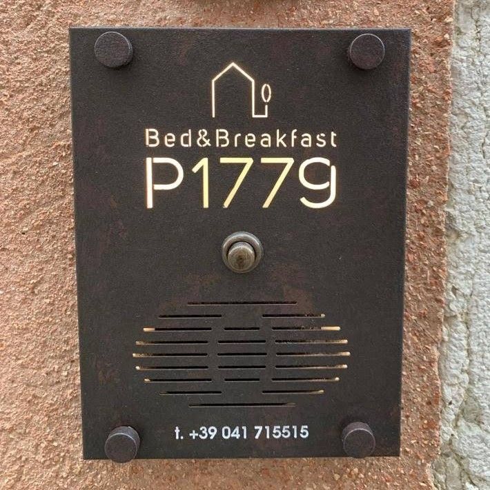 Pannello per citofono in metallo scuro per Bed & Breakfast P1779, con logo, pulsante del campanello, altoparlante e numero di telefono.