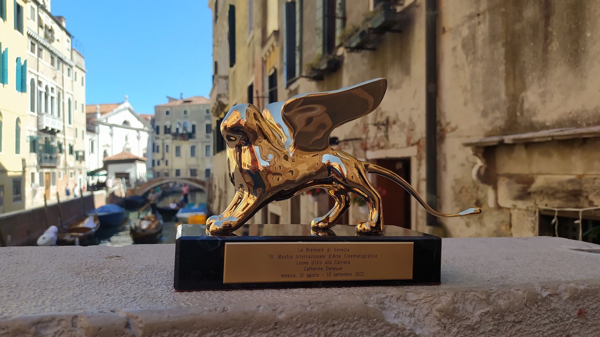 Un Leone d'Oro, premio assegnato al Festival del Cinema di Venezia, è esposto su una sporgenza che si affaccia su un canale di Venezia, in Italia.