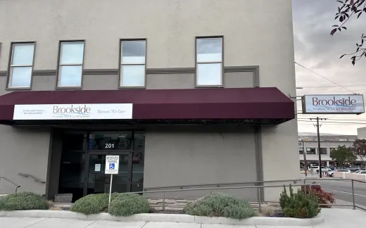 Building exterior with burgundy awning, windows, and sign that says 