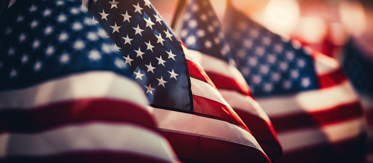 American flags waving in a row, with the blue star field and red stripes visible, focused.