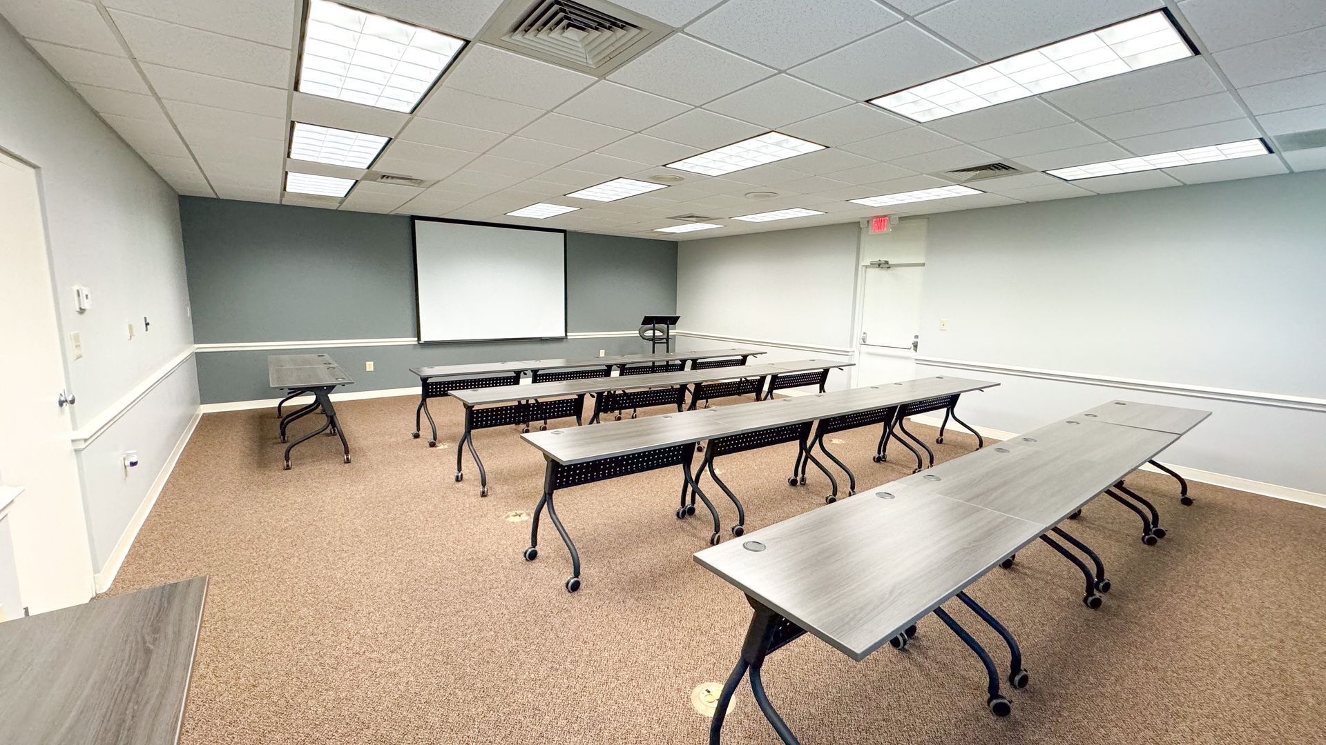 A conference room with tables and a projector screen.