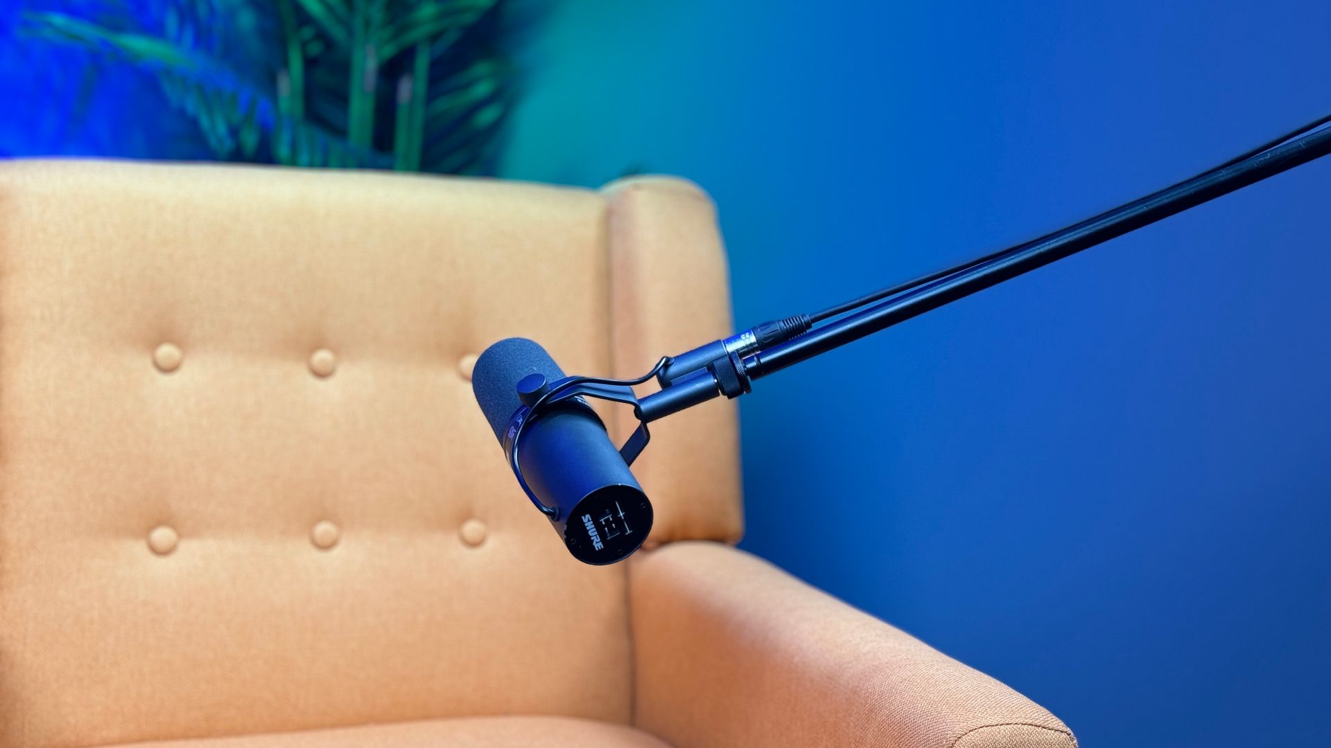 A microphone is sitting on a chair in front of a blue wall.