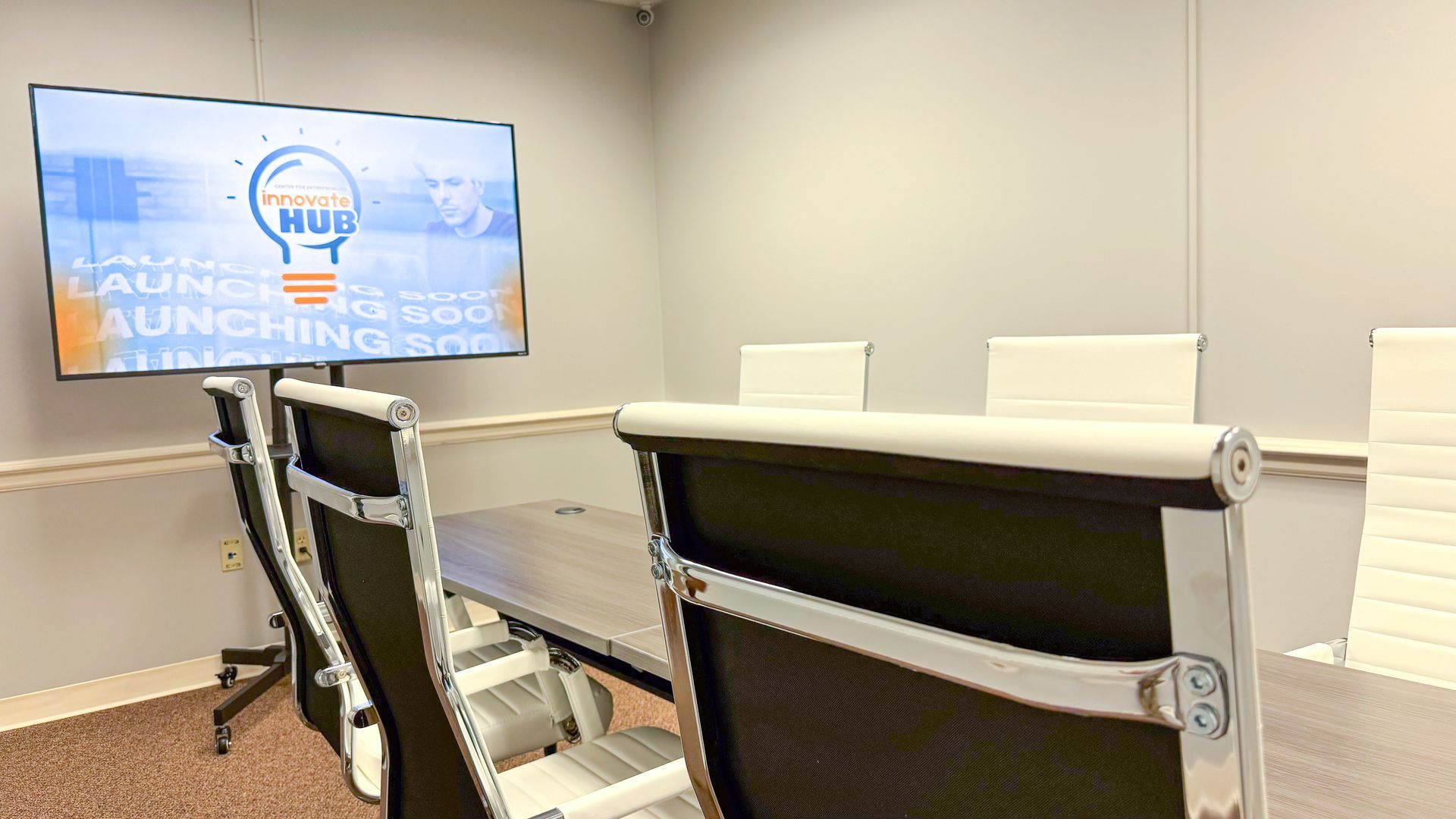 A conference room with a table and chairs and a flat screen tv.