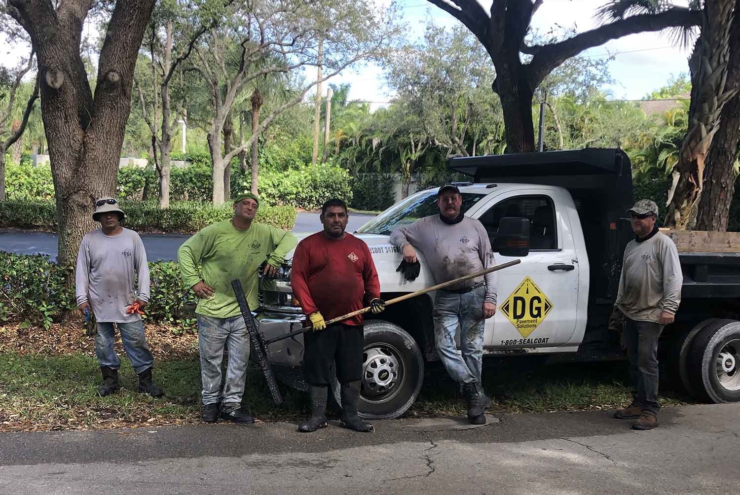 A group of men are standing in front of a dump truck.