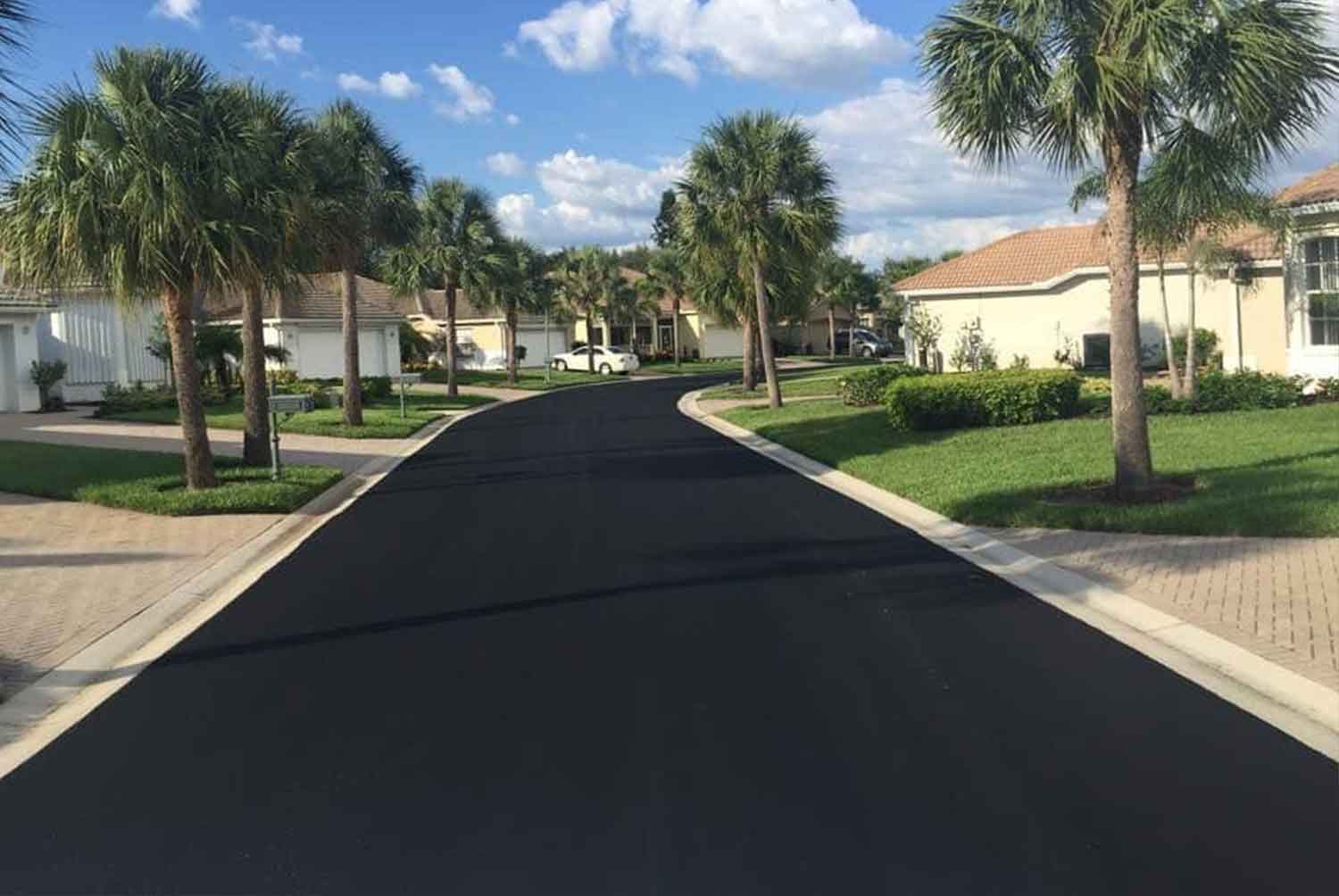 A residential street with palm trees on both sides of it.