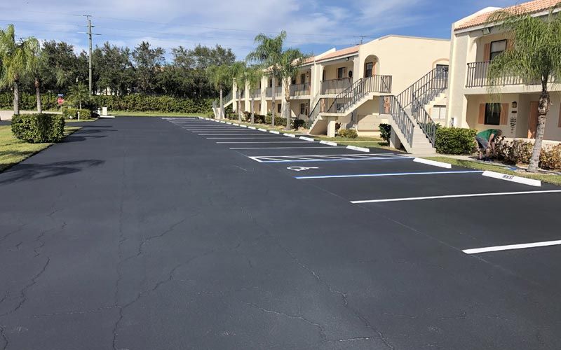 A parking lot in front of a row of apartment buildings.