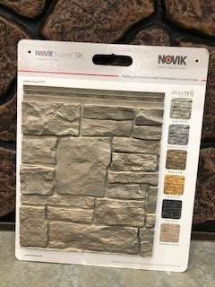 A Novik Stone SK display, showcasing a sample of stacked stone siding in shades of gray and beige.  Color swatches are shown on the right.