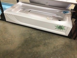 A white, rectangular shower base with a low profile is displayed on a shelf. There's a sticker that reads 