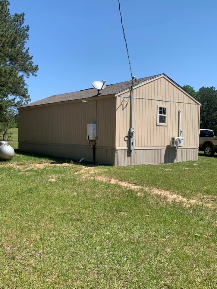 Person's hand holding a shiny silver faucet with plumbing tools scattered on a white countertop.