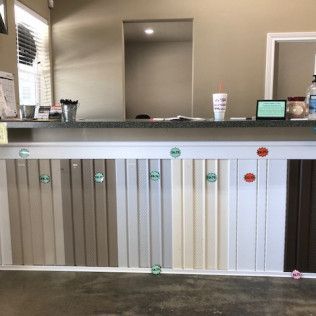 A display counter with various colors of siding samples. A window is visible to the left and a mirror in the background.