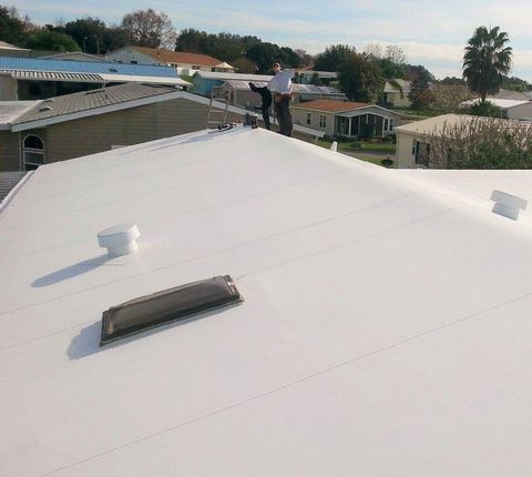 A man is standing on top of a white roof