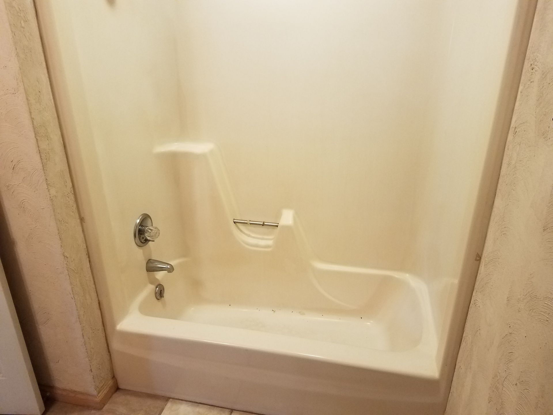 A dirty bathtub is sitting on the floor in a bathroom.