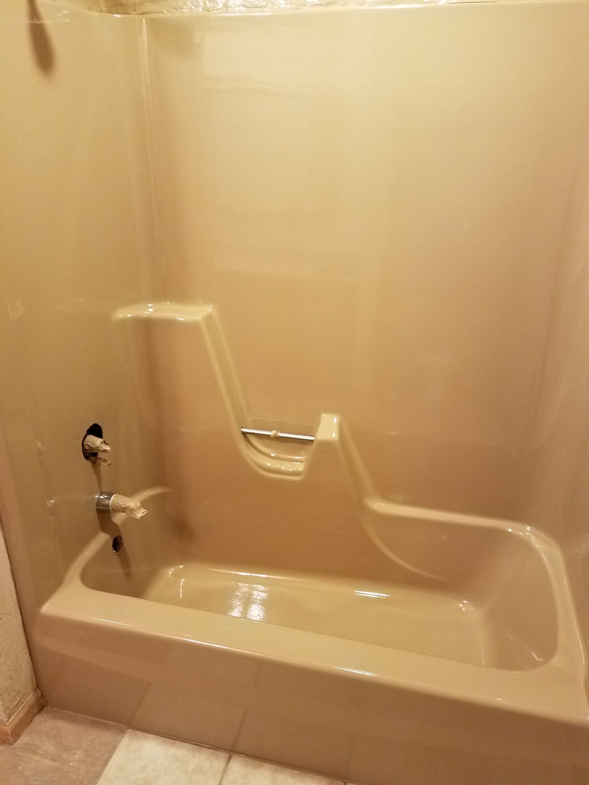 A white bathtub is sitting in a bathroom next to a marble wall.