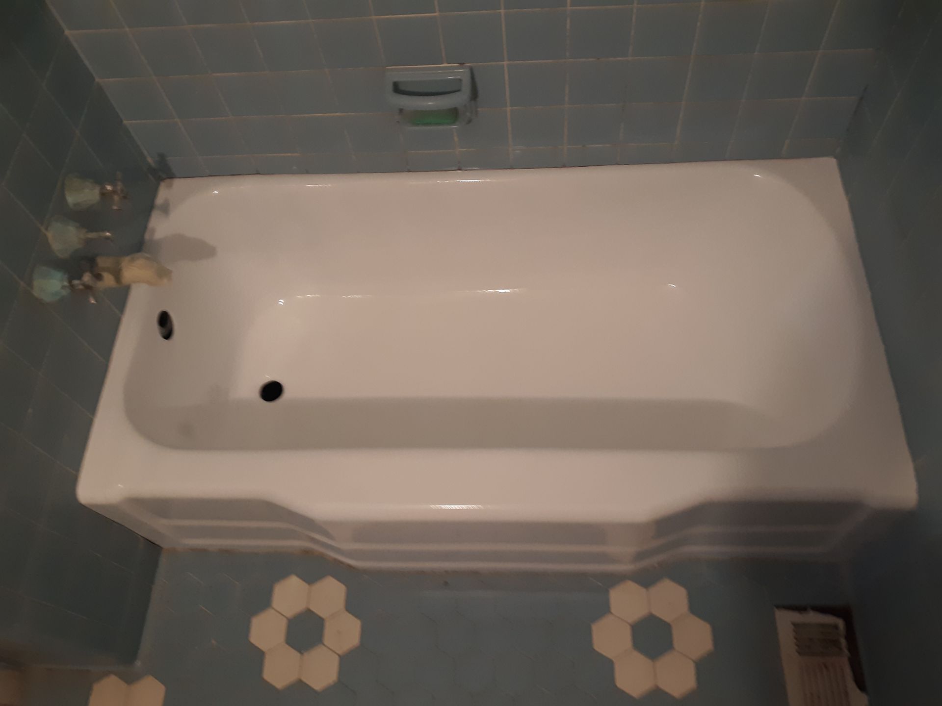 A white bathtub in a bathroom with blue tiles.