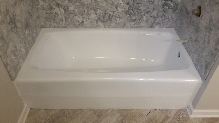 A white bathtub is sitting in a bathroom next to a marble wall.