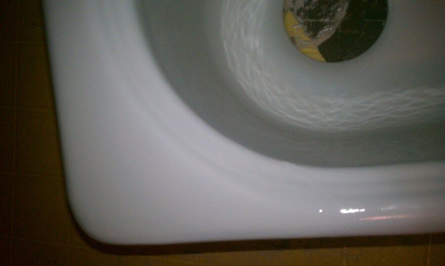 A close up of a bathtub with water running from a faucet.