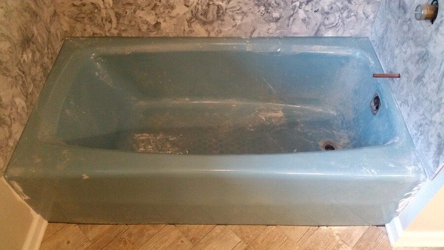 A blue bathtub is sitting in a bathroom next to a wall.