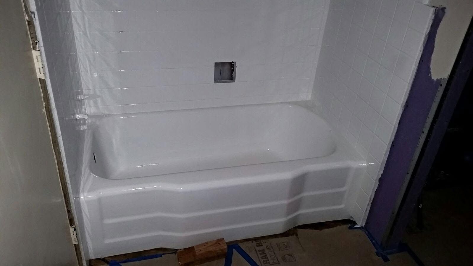 A white bathtub is sitting in a bathroom next to a marble wall.