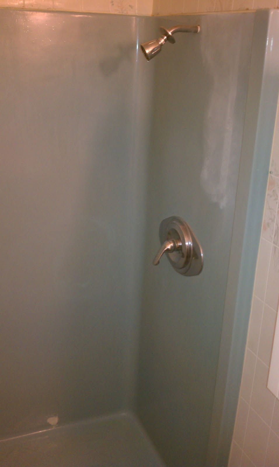 A dirty bathtub in a bathroom next to a toilet paper roll.