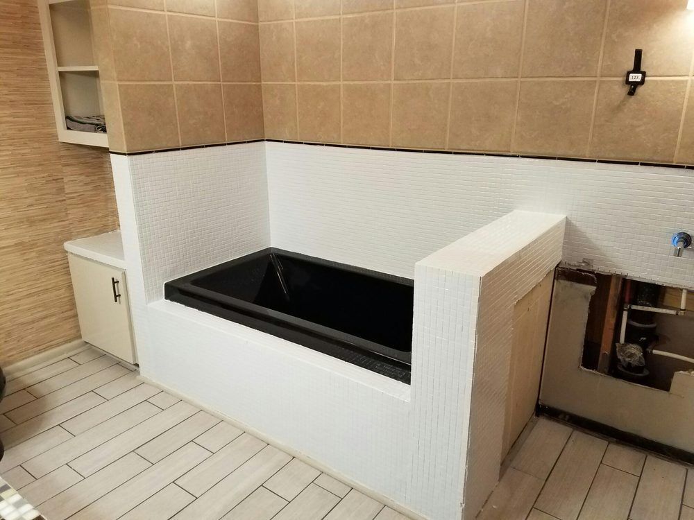 There is a black bathtub in the middle of the bathroom.