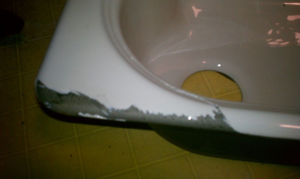 A bathtub with a hole in it and a drain.