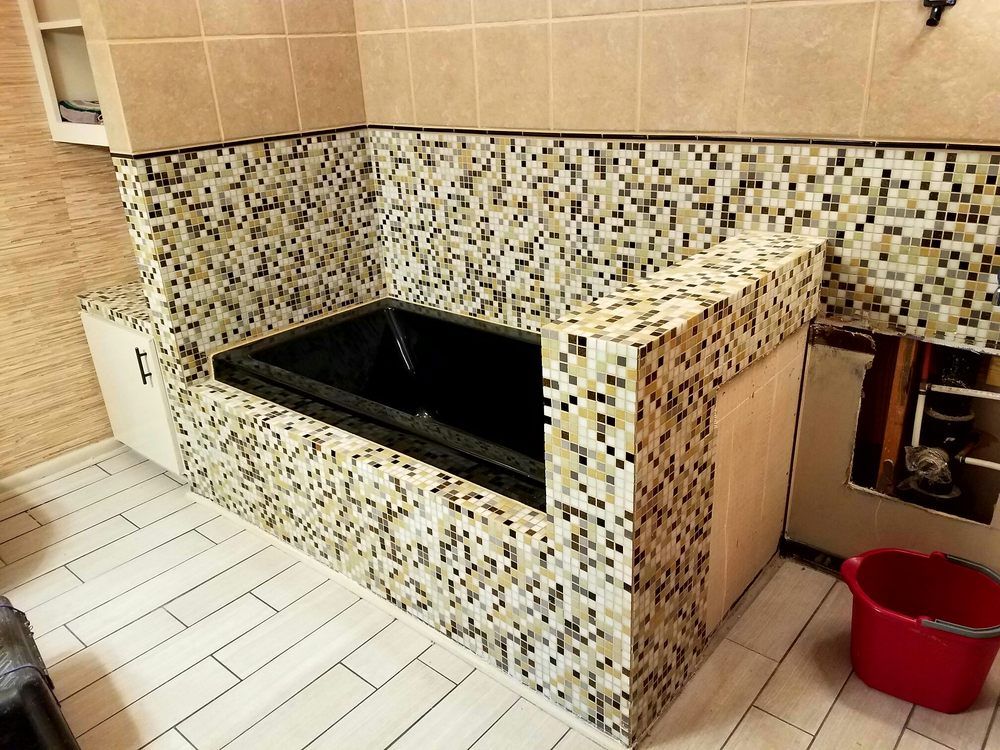 A bathroom with a black bathtub and a red bucket
