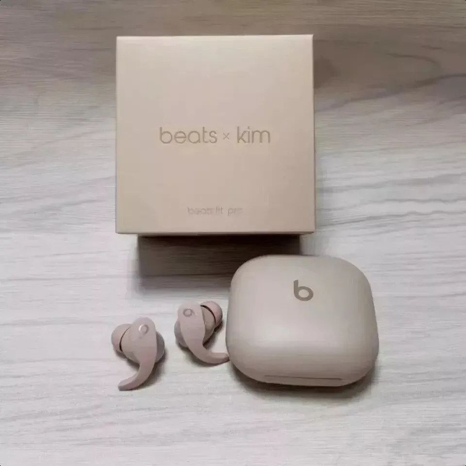 Un par de auriculares Beats x Kim están sobre una mesa de madera.