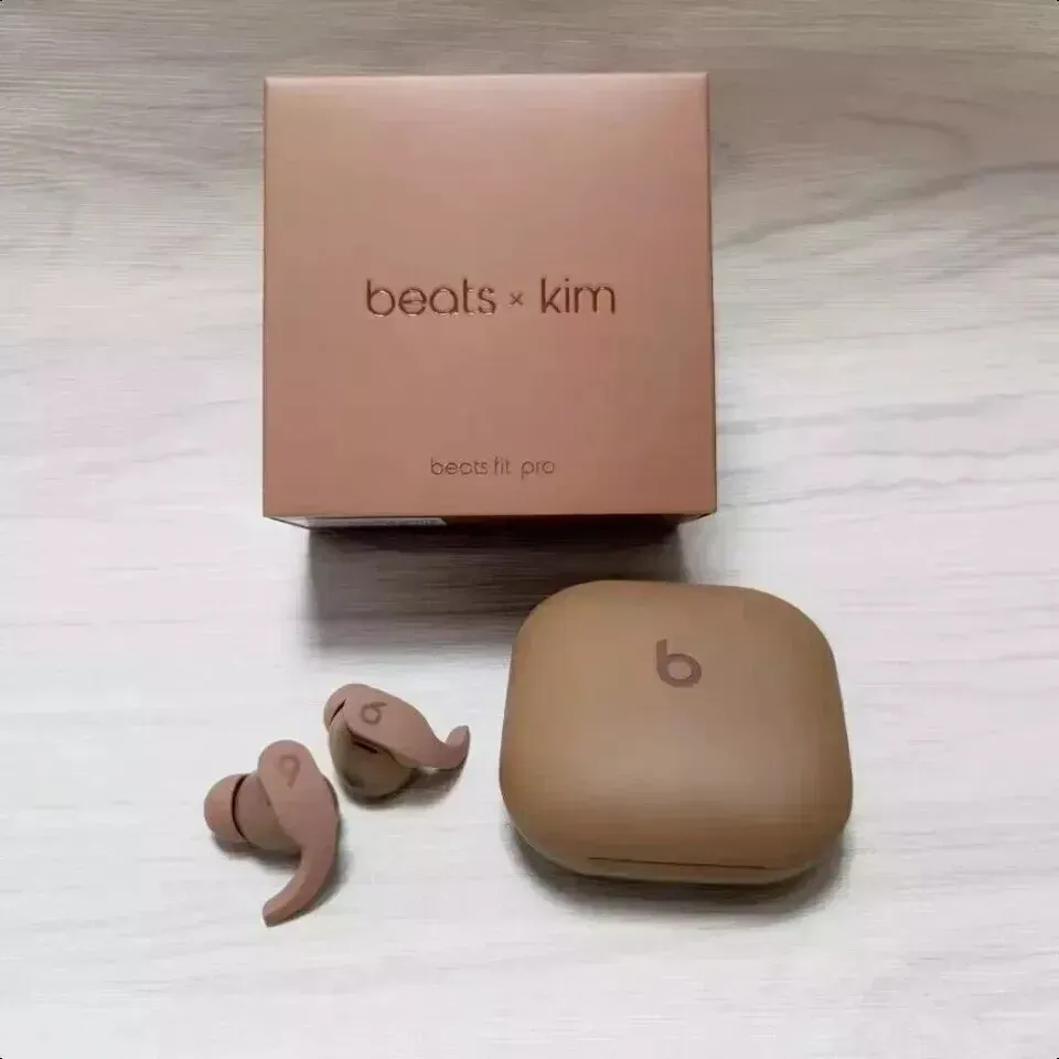 Un par de auriculares Beats by Kim están sobre una mesa al lado de su caja.