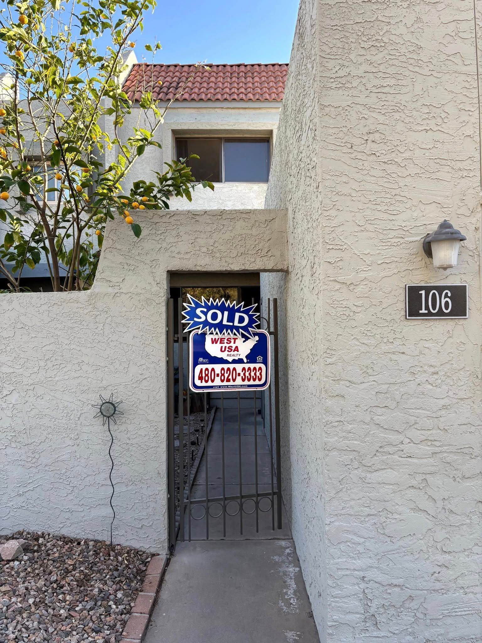 view of a condominium with barrel tile roof and lemon tree in front 