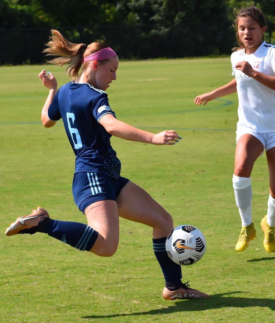 Female Sporting Arkansas player preparing to kick the ball past the defender.