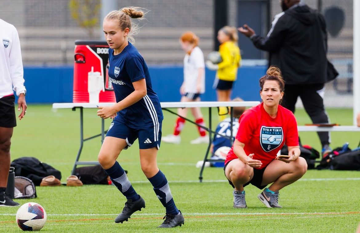 Sporting Arkansas girl player being watched by coach.