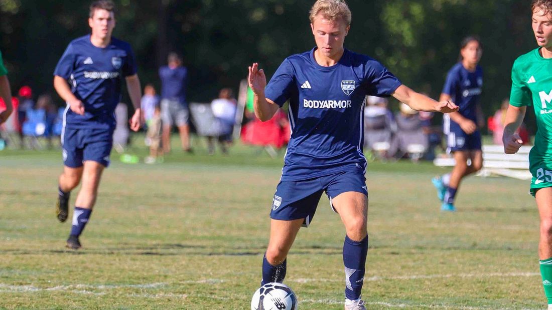 Sporting Arkansas player controlling the ball with opponent chasing him.