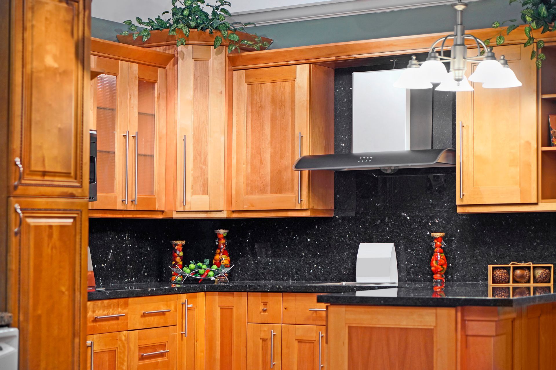 Wooden cabinets on a kitchen counter, with black granite countertops.
