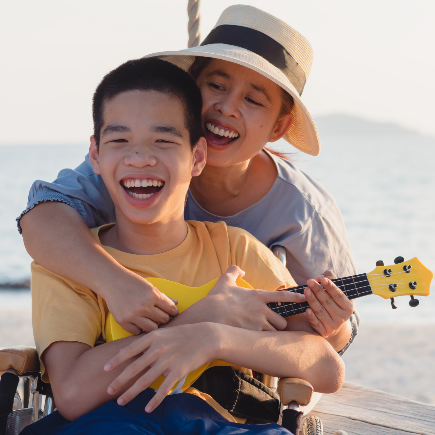 Young man with disability carrying a ukulele while his mom wraps her arms around him and the ukulele