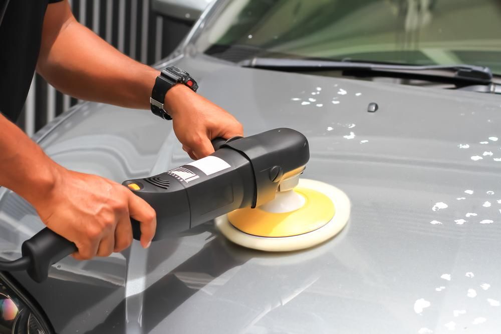 A Man is Polishing a Car With a Machine — Precise Detailing Specialists in Emerald, QLD