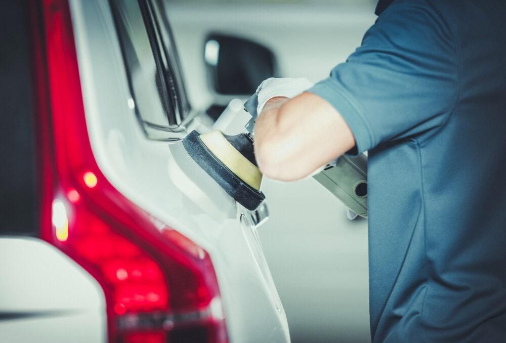 A Man is Polishing a Car With a Machine — Precise Detailing Specialists in Emerald, QLD