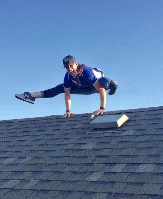 A man in a blue shirt is standing on a roof