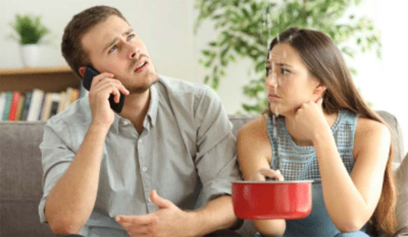 A man is talking on a cell phone while a woman holds a pot.
