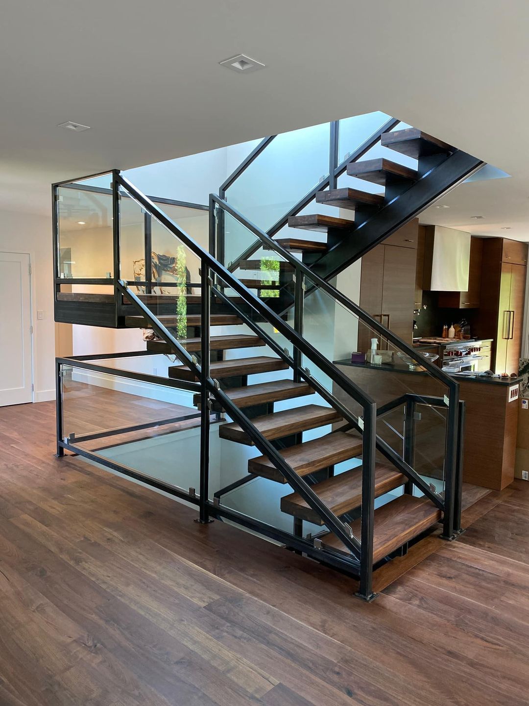 A wooden staircase with a glass railing in a house.