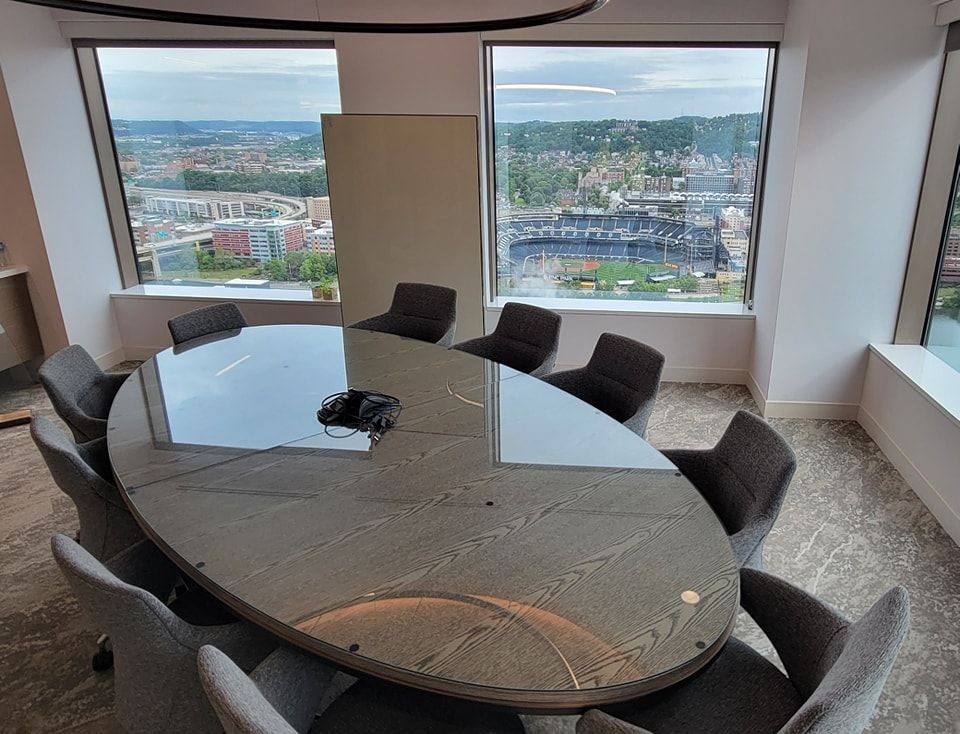 A conference room with a round table and chairs and a large window.