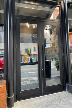 A black double glass door is open to a store.