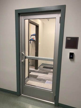 A glass door in a hallway with a sign on the wall.