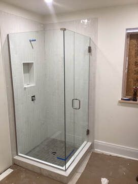 A bathroom with a shower stall and a window.