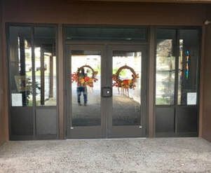 A man is standing in front of a door with a wreath on it.