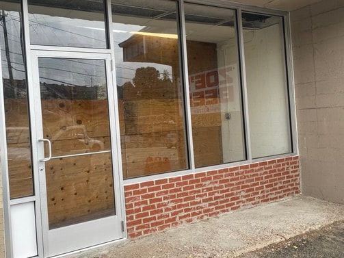 An empty store front with a brick wall and a glass door.