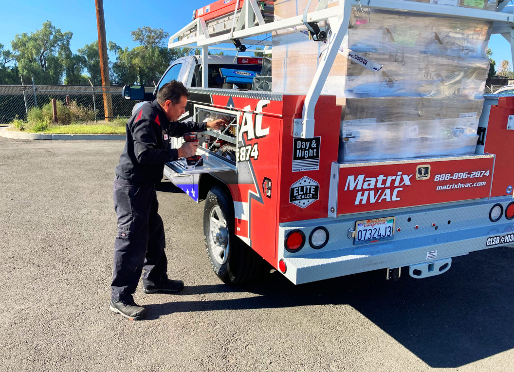 A man is working on the back of a matrix hvac truck.