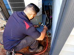 A man is working on an air conditioner in a room.