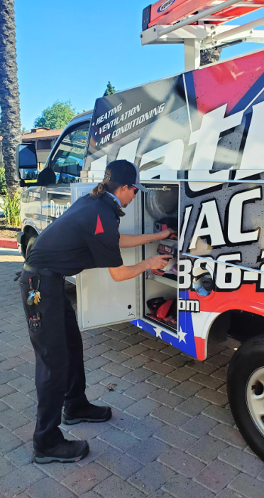 A man is standing next to a red white and blue truck.